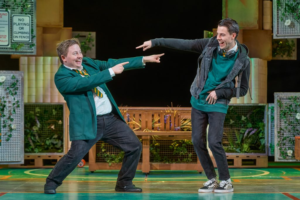Photo of two male cast members smiling and pointing at eachother
